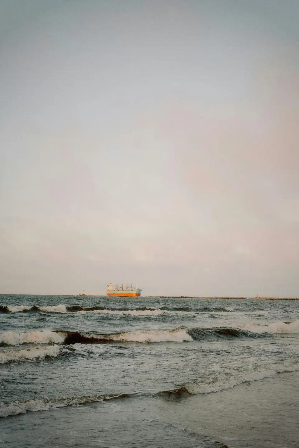 A real cargo ship on the sea at dusk, photographed by Ansis Kančs